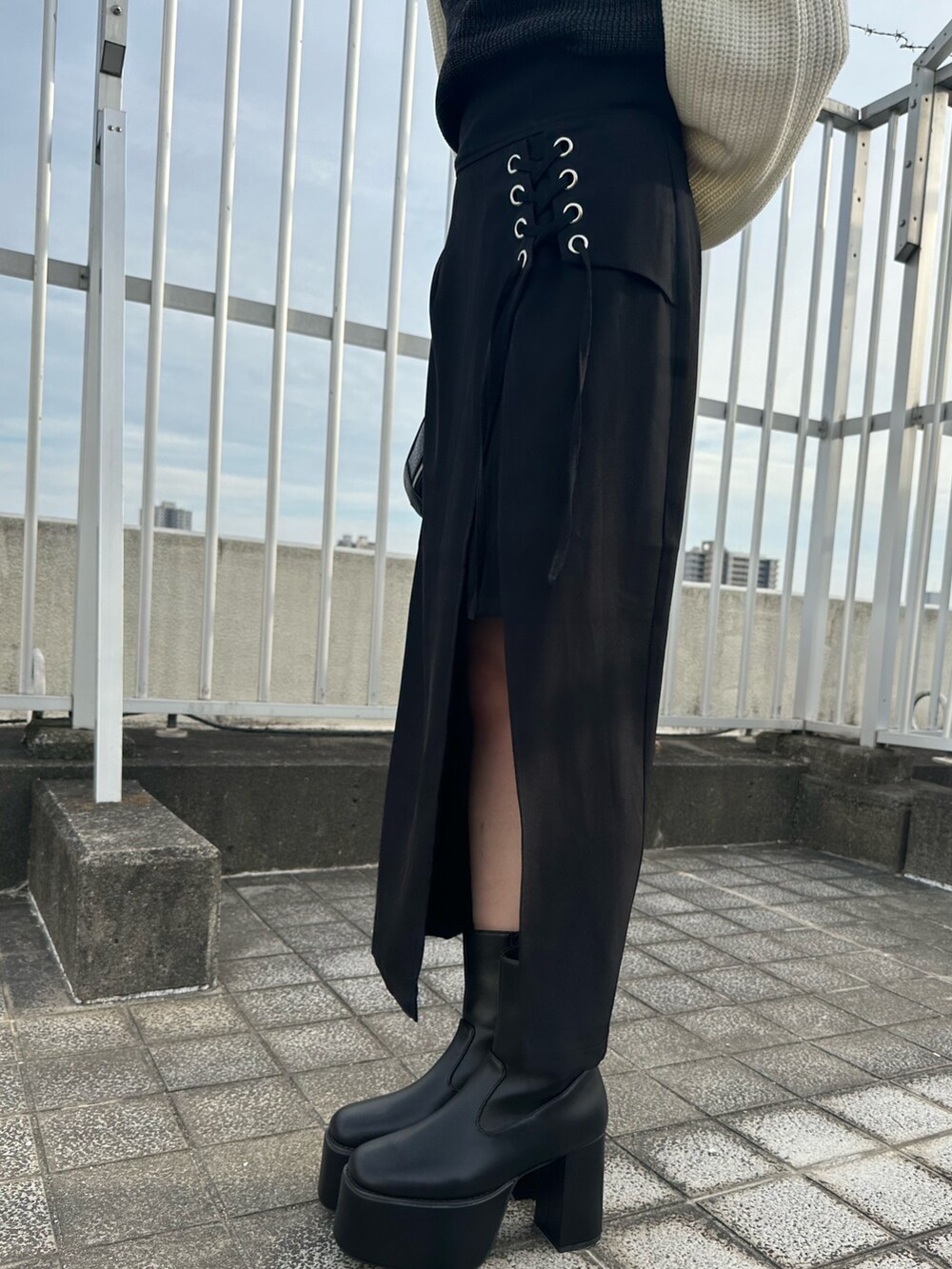 ブラック系のニット/セーター、ブラック系のスカート、ブラック系のブーツを着用したレディースの夏コーディネートの8枚目の写真