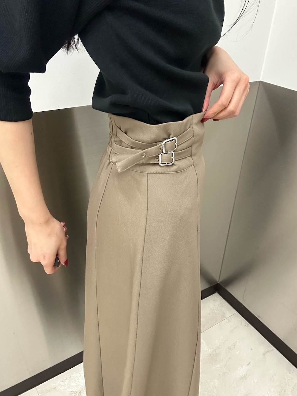 ベージュ系のスカート、ブラック系のニット/セーター、ブラック系のブーツを着用したレディースの夏コーディネートの8枚目の写真