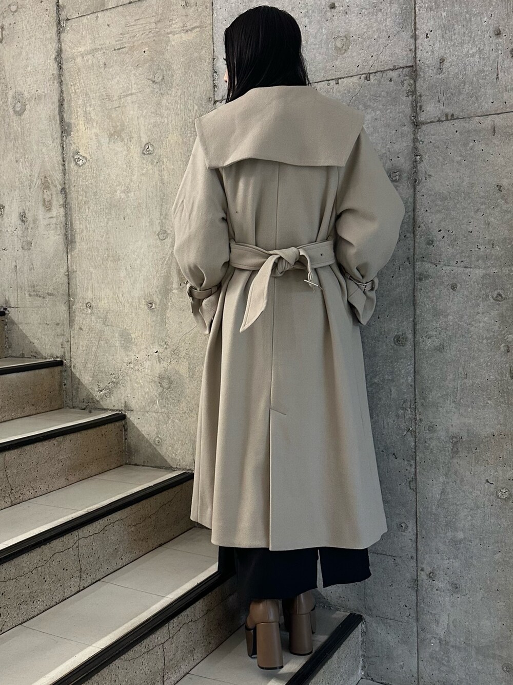 ブラック系のスカート、ホワイト系のニット/セーター、ブラウン系のブーツを着用したレディースの冬コーディネートの3枚目の写真