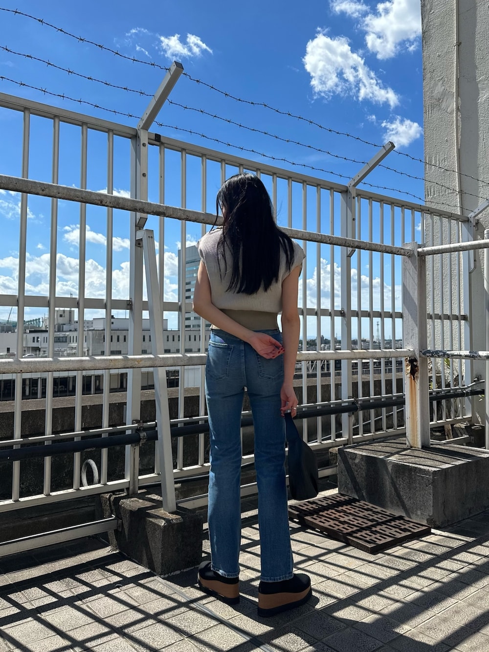 ホワイト系のニット/セーター、ブルー系のデニムパンツ、ブラック系のブーツを着用したレディースの夏コーディネートの4枚目の写真