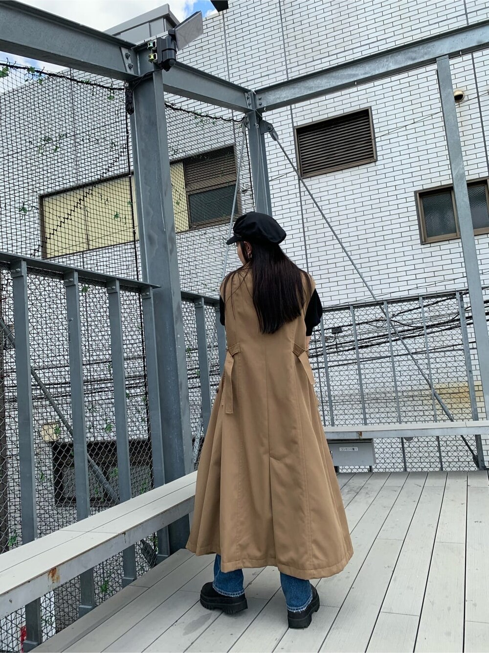 ブラック系のニット/セーター、ブルー系のデニムパンツ、ブラウン系のトレンチコートを着用したレディースの夏コーディネートの4枚目の写真