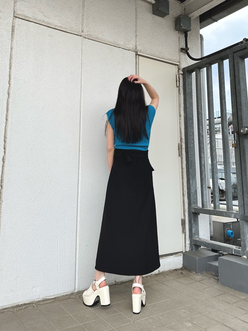 ブルー系のニット/セーター、ブラック系のスカート、ホワイト系のサンダルを着用したレディースの春コーディネートの4枚目の写真