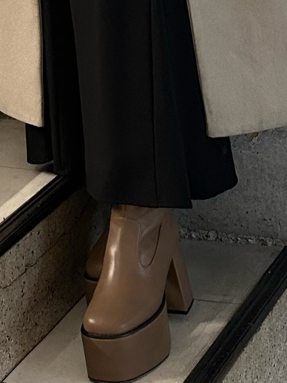 ブラック系のスカート、ホワイト系のニット/セーター、ブラウン系のブーツを着用したレディースの冬コーディネートの7枚目の写真