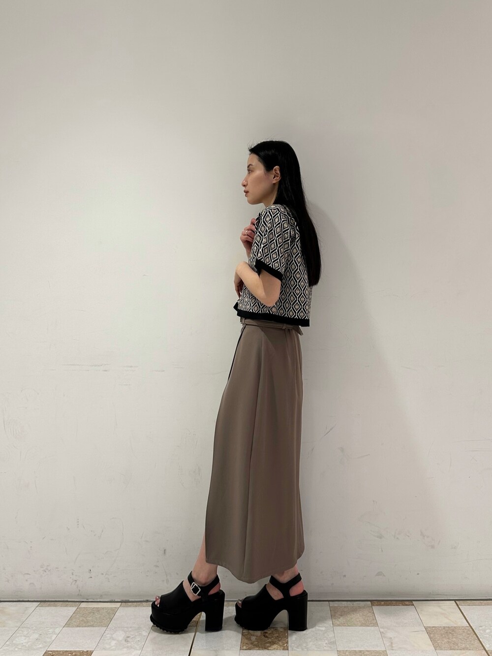 ブラウン系のスカート、ブラック系のポロシャツ、ブラック系のサンダルを着用したレディースの春コーディネートの2枚目の写真