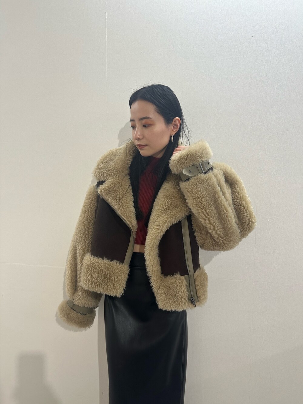 ブラック系のスカート、ブラウン系のムートンコート、レッド系のニット/セーターを着用したレディースの冬コーディネートの4枚目の写真