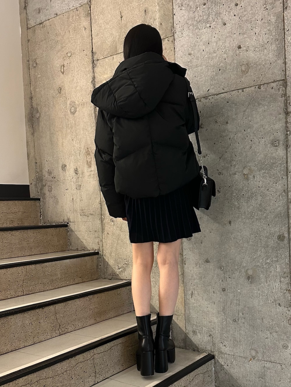 ブラック系のダウンジャケット/コート、ブラック系のブーツ、ブラック系のワンピースを着用したレディースの冬コーディネートの2枚目の写真