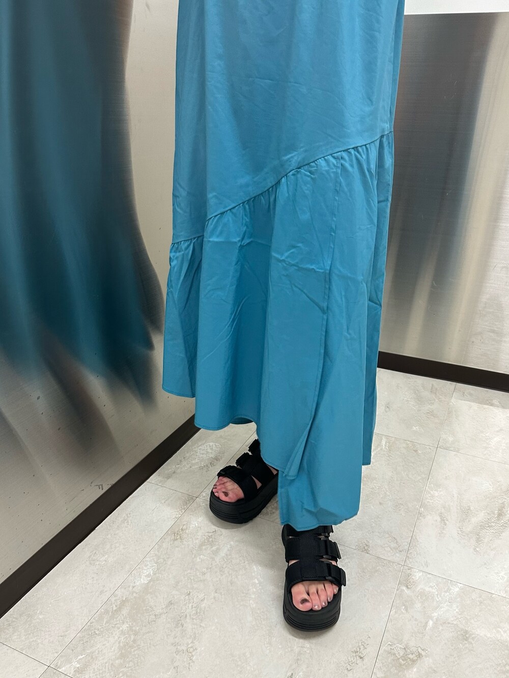 ブルー系のワンピース、ブラック系のTシャツ/カットソー、ブラック系のサンダルを着用したレディースの春コーディネートの7枚目の写真