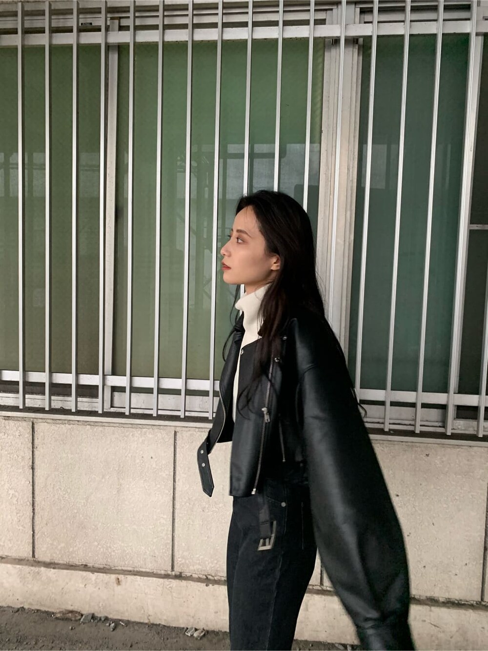 ブラック系のデニムパンツ、ブラウン系のブーツ、ブラック系のライダースジャケットを着用したレディースの秋コーディネートの3枚目の写真