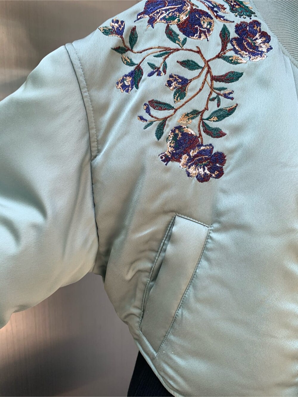 グリーン系のブルゾン、ブラック系のワンピース、ブラック系のブーツを着用したレディースの秋コーディネートの3枚目の写真