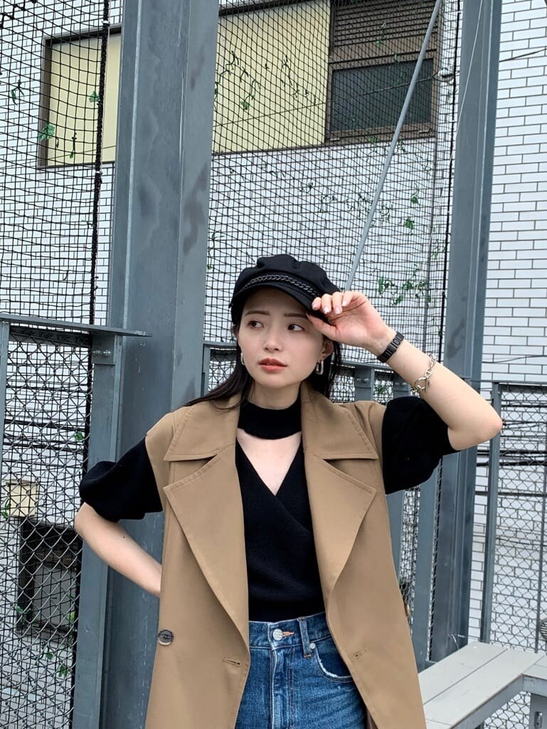 ブラック系のニット/セーター、ブルー系のデニムパンツ、ブラウン系のトレンチコートを着用したレディースの夏コーディネートの5枚目の写真