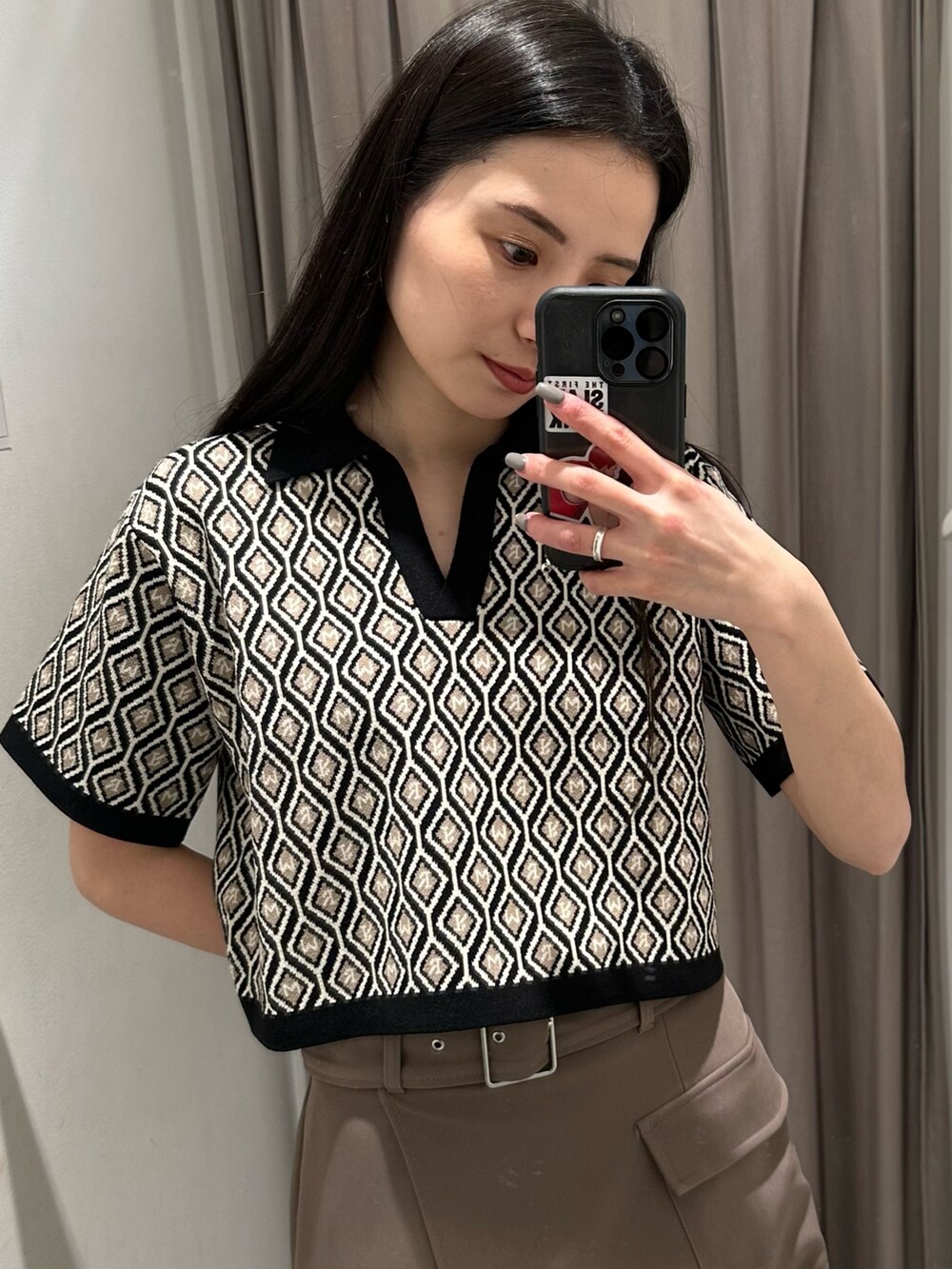 ブラウン系のスカート、ブラック系のポロシャツ、ブラック系のサンダルを着用したレディースの春コーディネートの4枚目の写真