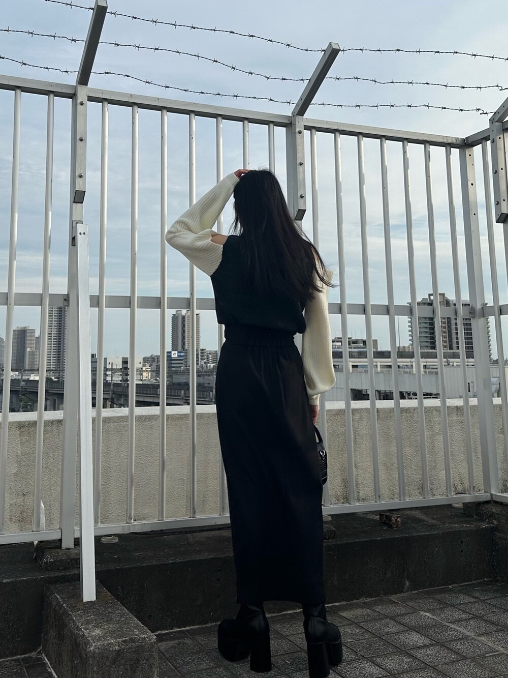 ブラック系のニット/セーター、ブラック系のスカート、ブラック系のブーツを着用したレディースの夏コーディネートの4枚目の写真