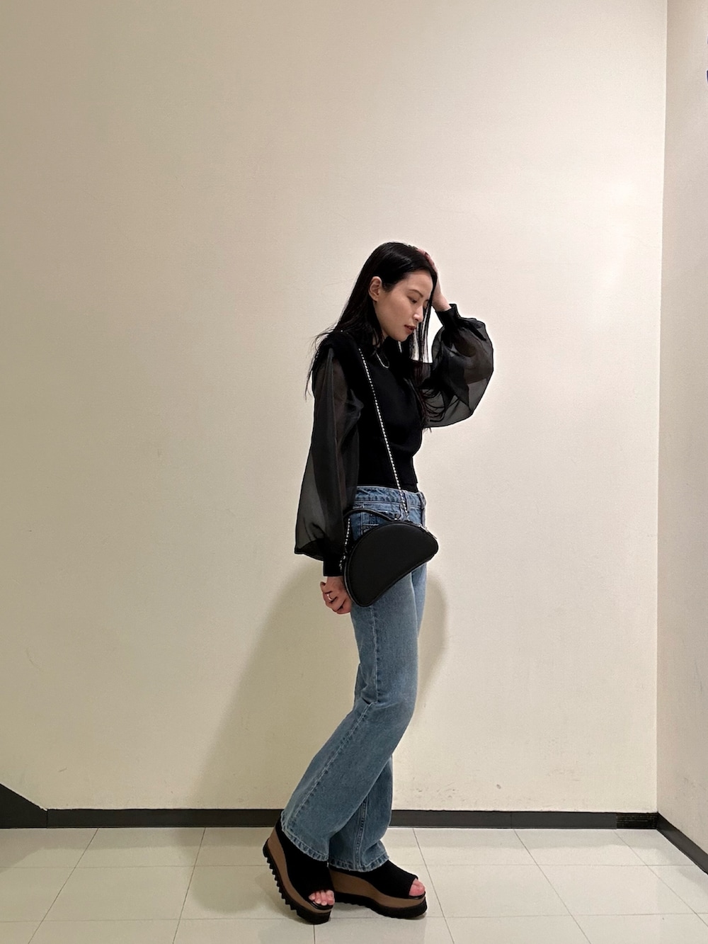 ブラック系のニット/セーター、ブルー系のデニムパンツを着用したレディースの春コーディネートの2枚目の写真