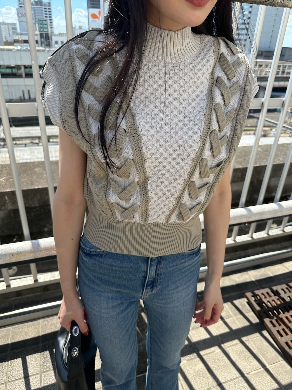 ホワイト系のニット/セーター、ブルー系のデニムパンツ、ブラック系のブーツを着用したレディースの夏コーディネートの7枚目の写真