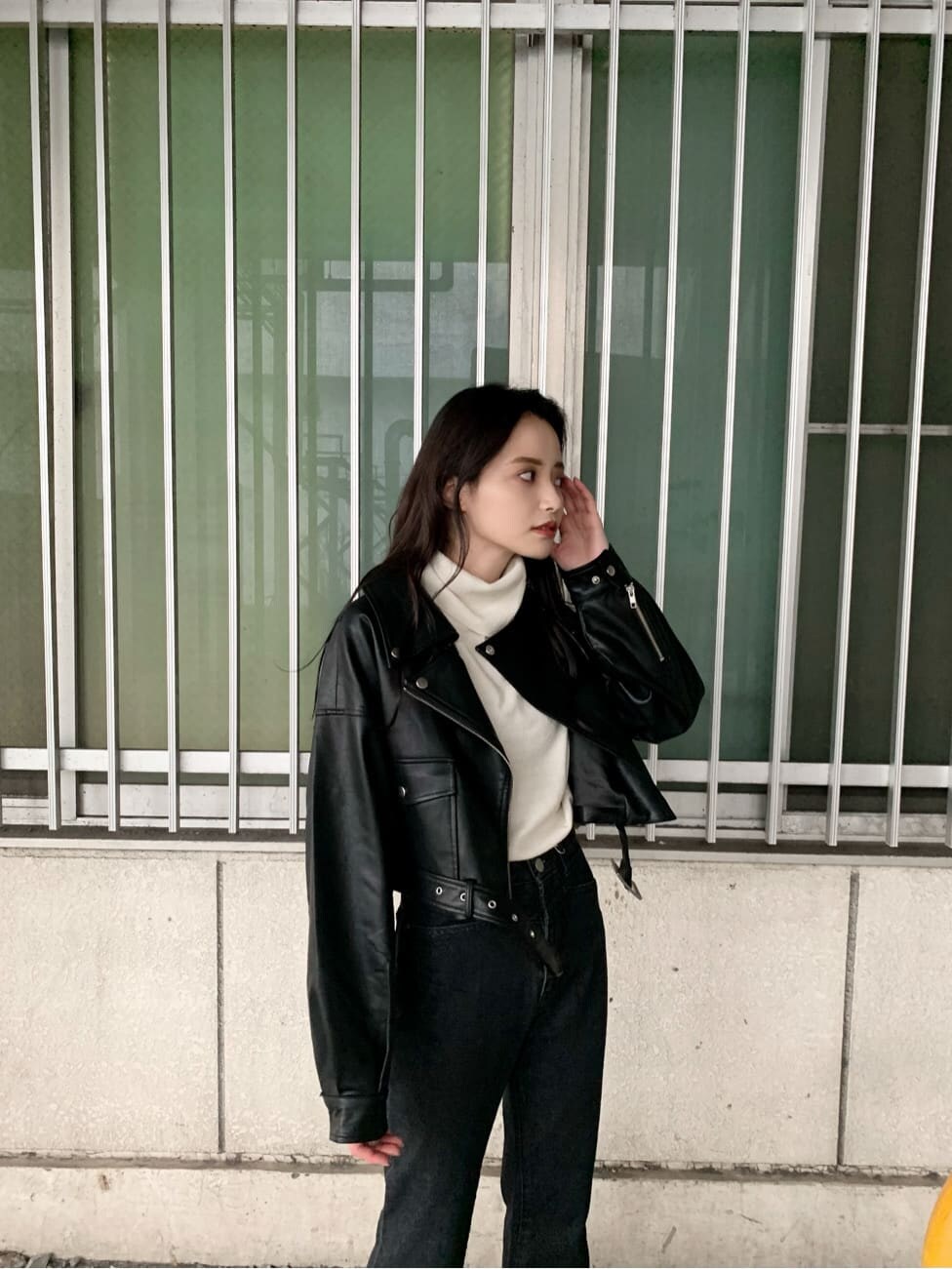 ブラック系のデニムパンツ、ブラウン系のブーツ、ブラック系のライダースジャケットを着用したレディースの秋コーディネートの2枚目の写真