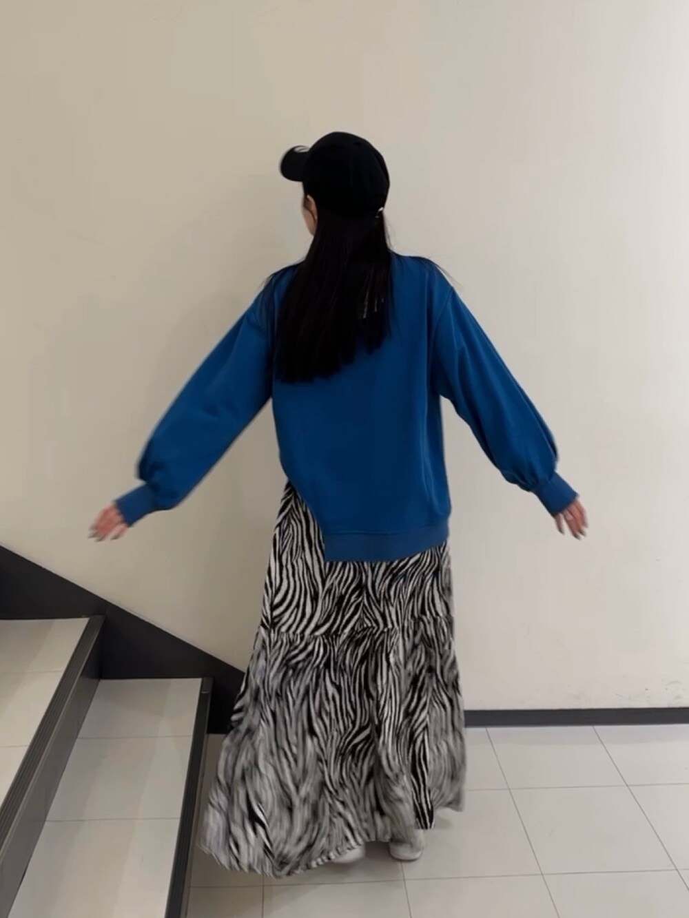 ブルー系のTシャツ/カットソー、ホワイト系のスカート、ブラック系のキャップを着用したレディースの春コーディネートの2枚目の写真