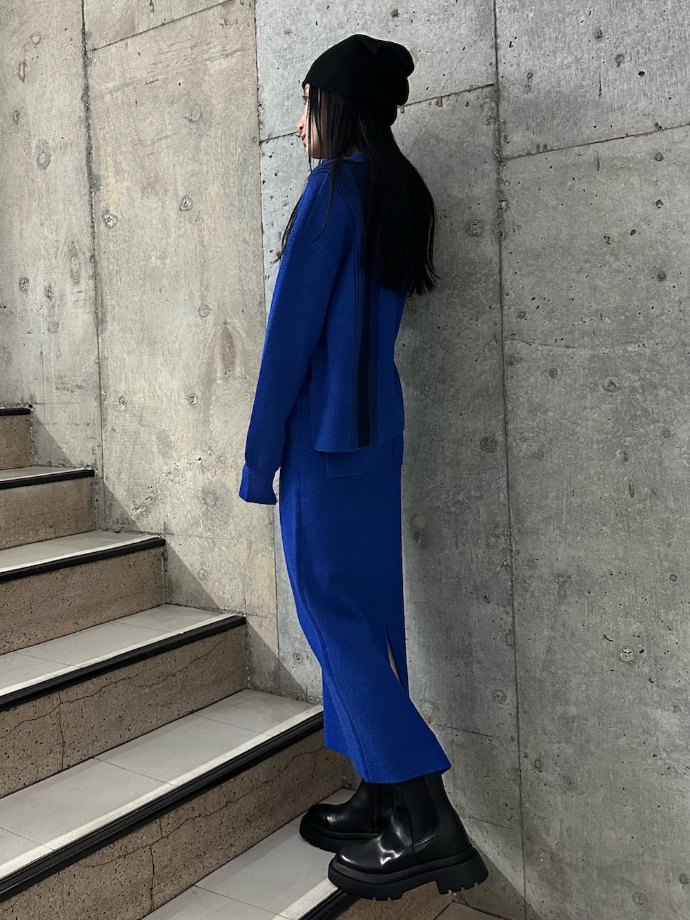 ブルー系のニット/セーター、ブルー系のスカート、ブラック系のブーツを着用したレディースの冬コーディネートの2枚目の写真