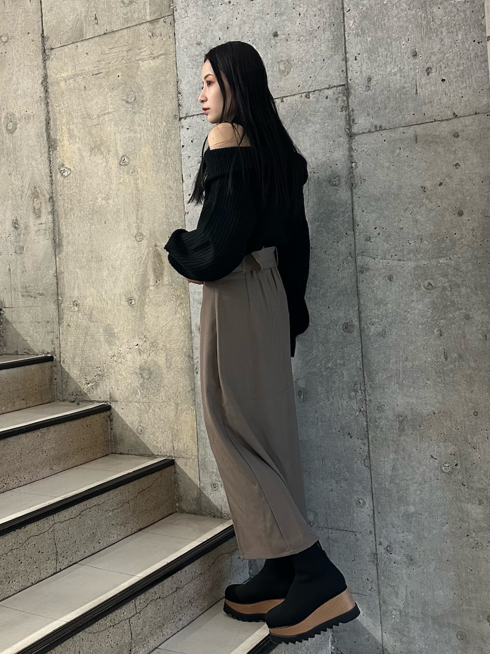 ブラウン系のスカート、ブラック系のニット/セーター、ブラック系のブーツを着用したレディースの冬コーディネートの3枚目の写真