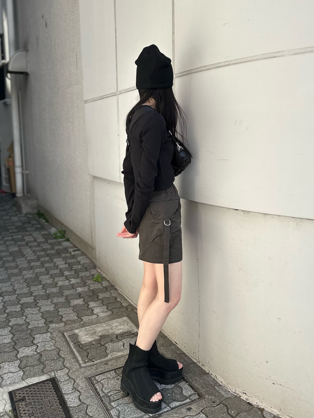 ベージュ系のスカート、ブラック系のTシャツ/カットソー、ブラック系のブーツを着用したレディースの冬コーディネートの2枚目の写真