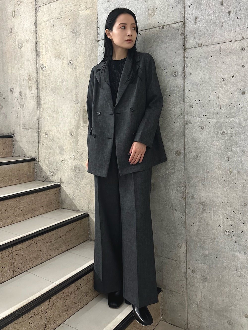 グレー系のスラックス、ブラック系のブーツ、グレー系のテーラードジャケットを着用したレディースの秋コーディネートの2枚目の写真