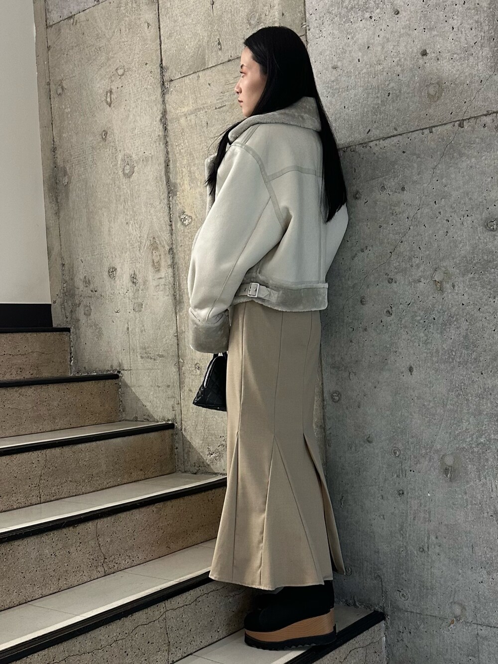 ベージュ系のスカート、グレー系のムートンコート、ブラック系のニット/セーターを着用したレディースの冬コーディネートの3枚目の写真