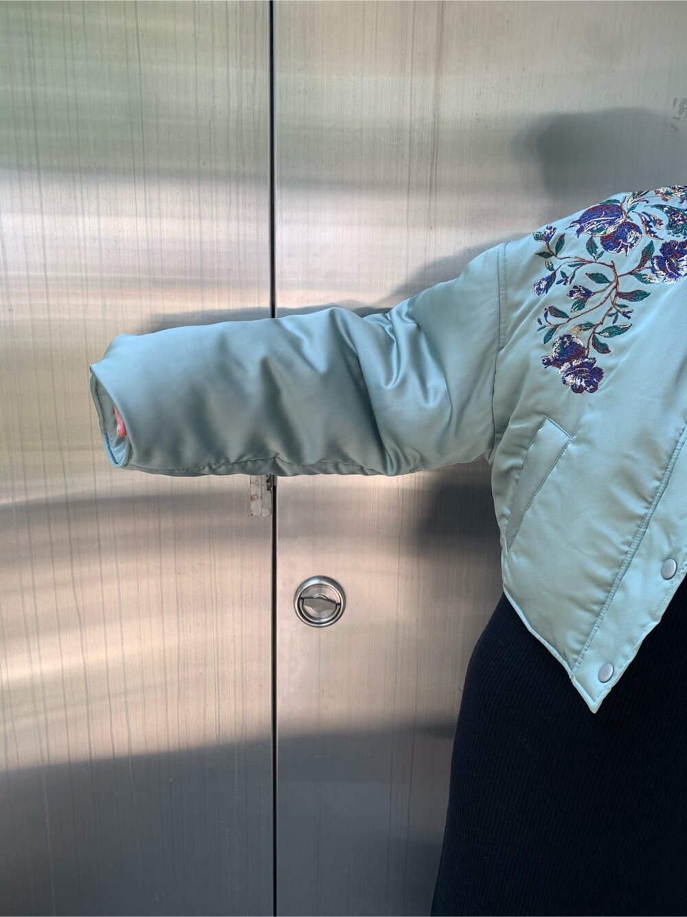 グリーン系のブルゾン、ブラック系のワンピース、ブラック系のブーツを着用したレディースの秋コーディネートの4枚目の写真