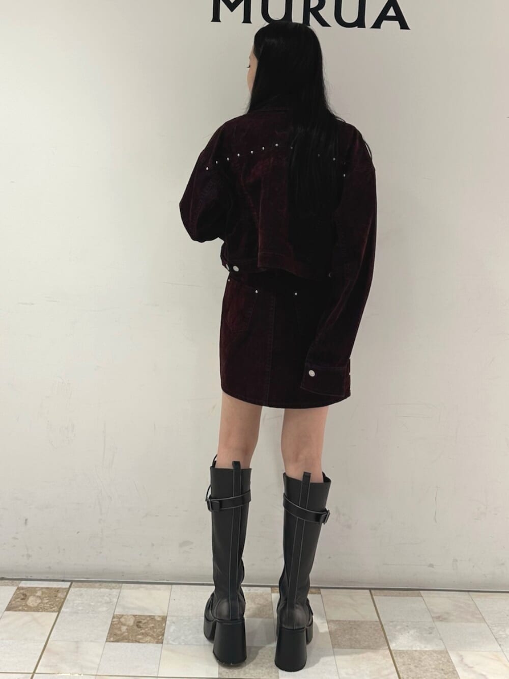 レッド系のスカート、レッド系のデニムジャケット、ブラック系のブーツを着用したレディースの夏コーディネートの2枚目の写真