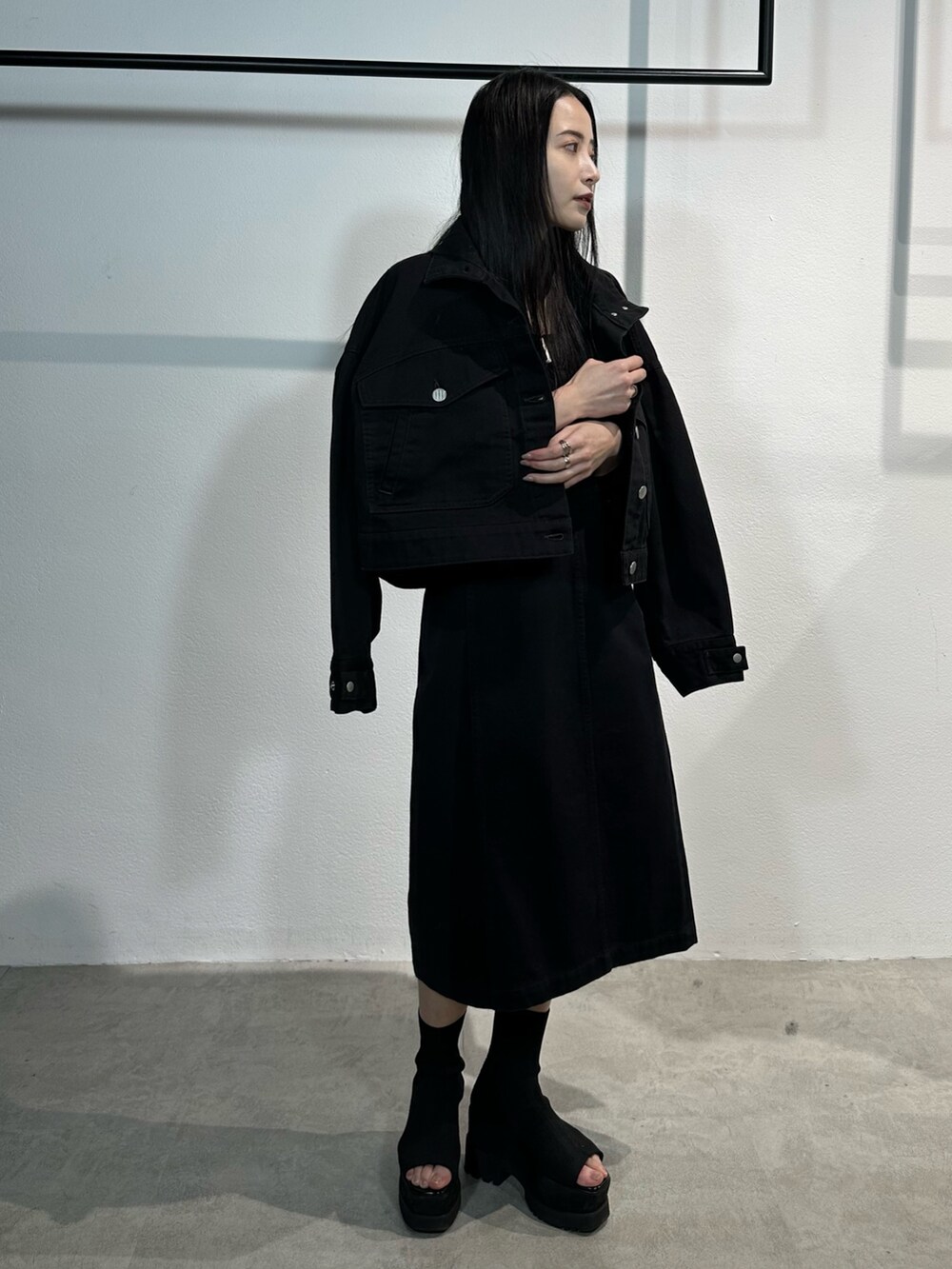 ブラック系のワンピース、ブラック系のデニムジャケット、ブラック系のブーツを着用したレディースの冬コーディネートの2枚目の写真