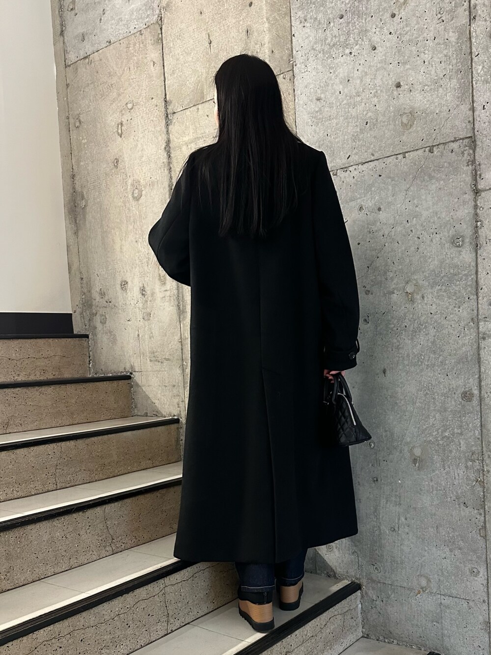 ブラック系のブーツ、ブラック系のチェスターコート、ブラック系のニット/セーターを着用したレディースの冬コーディネートの2枚目の写真