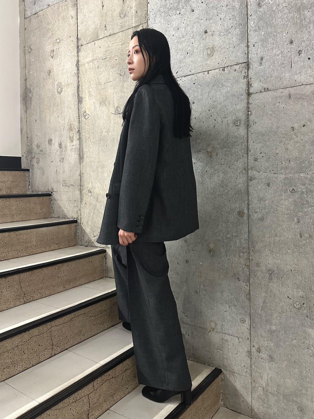 グレー系のスラックス、ブラック系のブーツ、グレー系のテーラードジャケットを着用したレディースの秋コーディネートの3枚目の写真