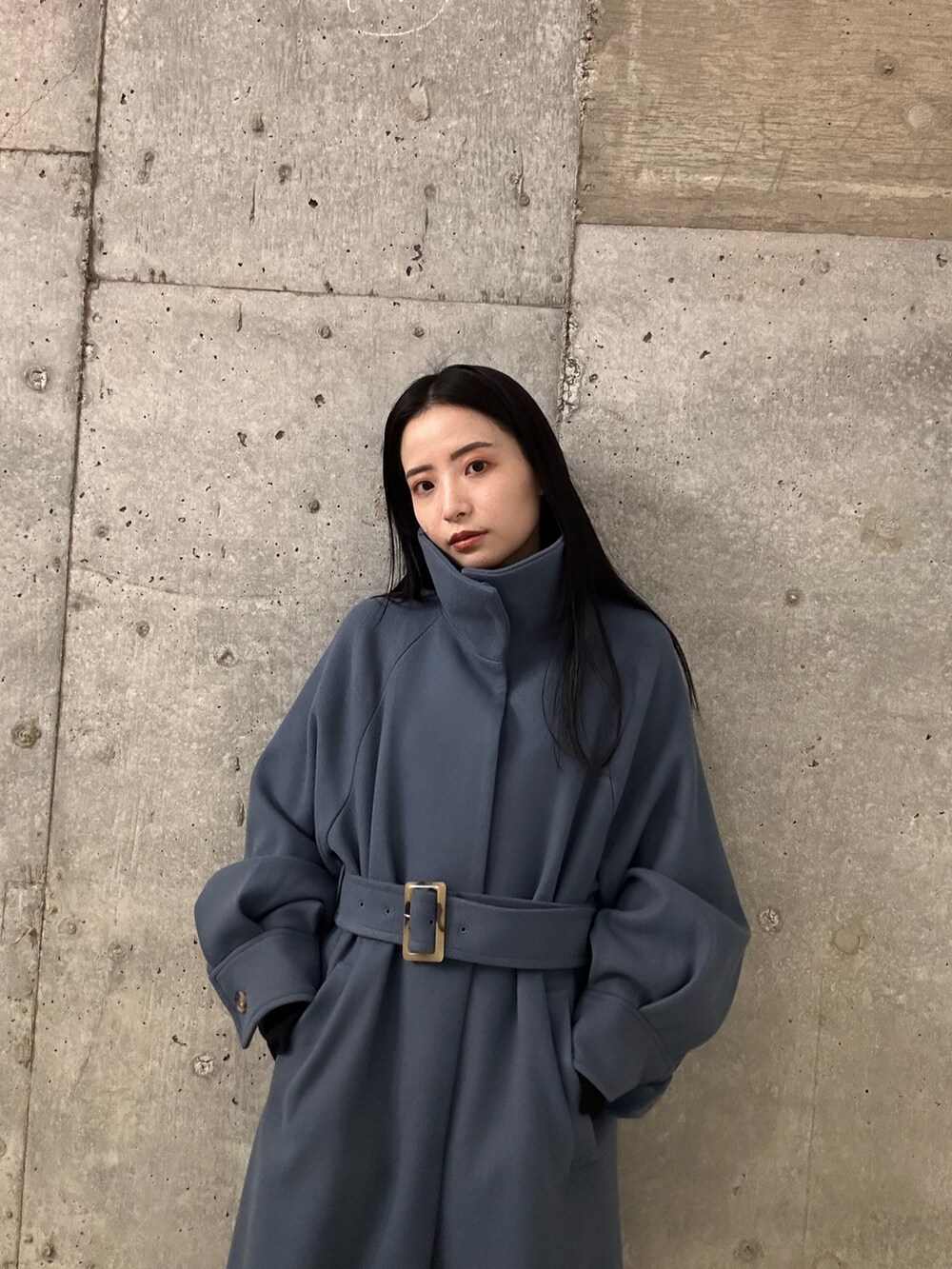 ブルー系のステンカラーコート、ブラック系のブーツを着用したレディースの秋コーディネートの4枚目の写真