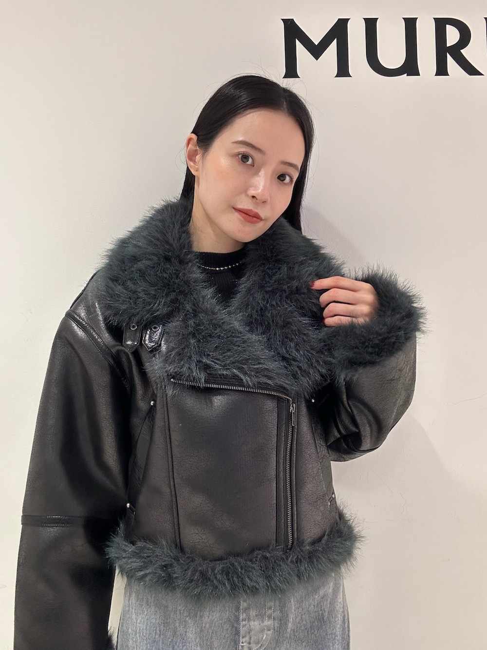 グレー系のデニムパンツ、ブラック系のブーツ、ブラック系のムートンコートを着用したレディースの夏コーディネートの6枚目の写真