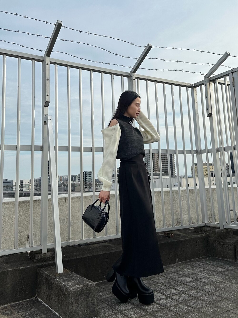 ブラック系のニット/セーター、ブラック系のスカート、ブラック系のブーツを着用したレディースの夏コーディネートの2枚目の写真