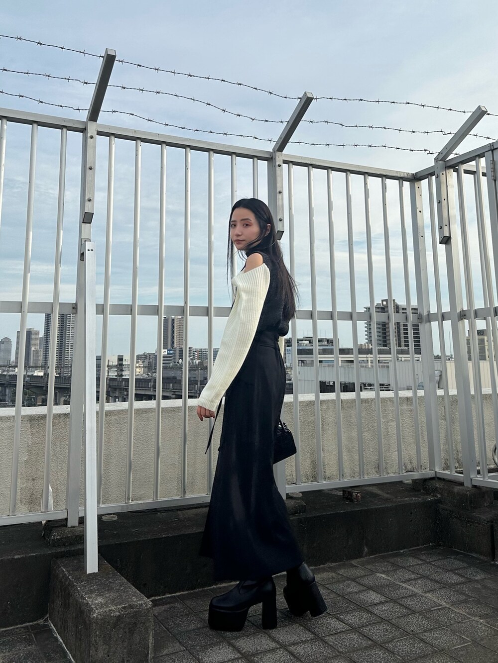 ブラック系のニット/セーター、ブラック系のスカート、ブラック系のブーツを着用したレディースの夏コーディネートの5枚目の写真