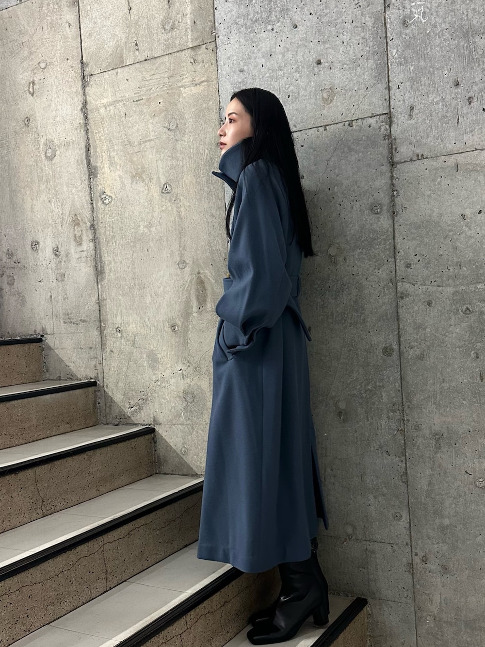 ブルー系のステンカラーコート、ブラック系のブーツを着用したレディースの秋コーディネートの2枚目の写真