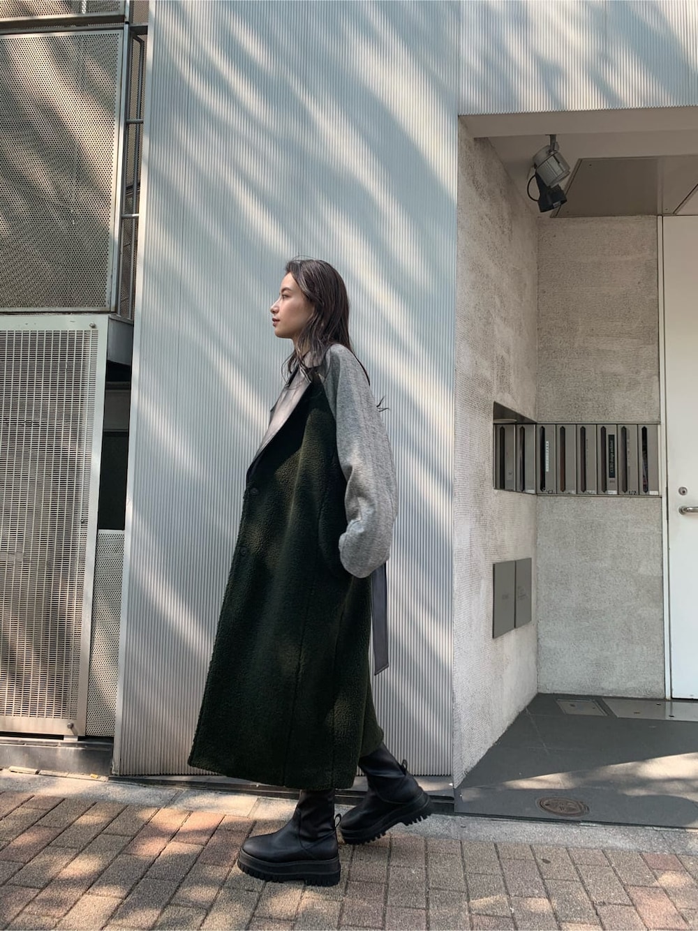 ブラック系のチェスターコート、ブラック系のワンピース、ブラック系のブーツを着用したレディースの秋コーディネートの6枚目の写真