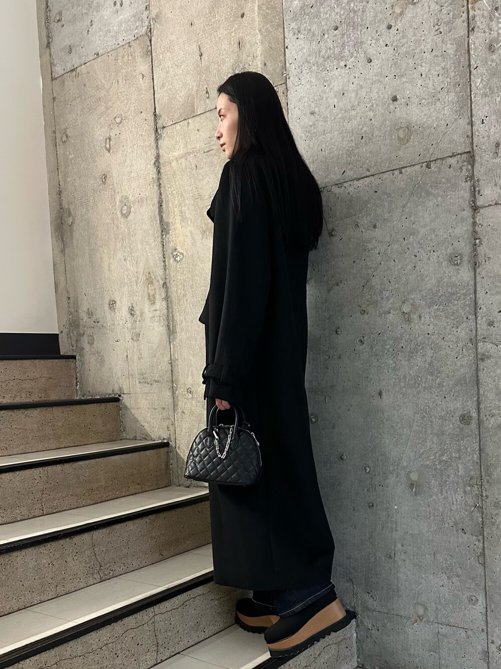 ブラック系のブーツ、ブラック系のチェスターコート、ブラック系のニット/セーターを着用したレディースの冬コーディネートの3枚目の写真