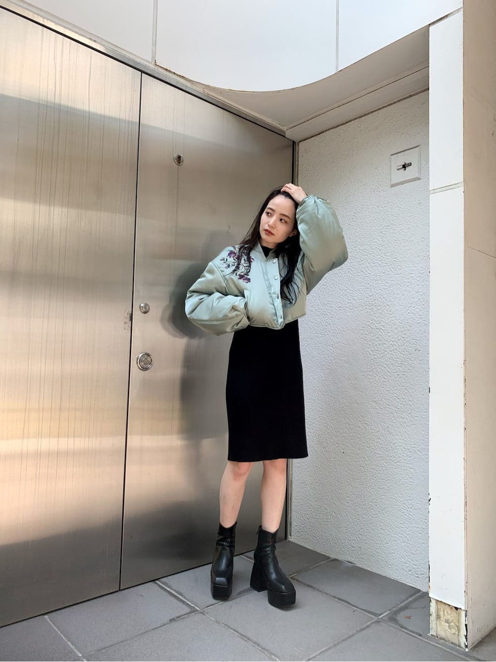 グリーン系のブルゾン、ブラック系のワンピース、ブラック系のブーツを着用したレディースの秋コーディネートの2枚目の写真