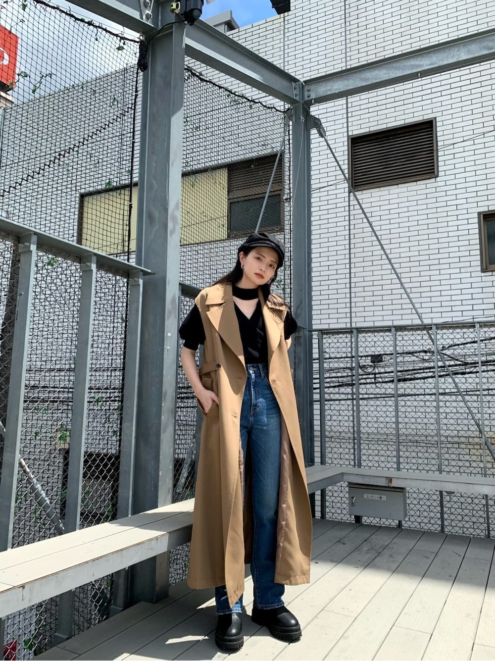 ブラック系のニット/セーター、ブルー系のデニムパンツ、ブラウン系のトレンチコートを着用したレディースの夏コーディネートの2枚目の写真