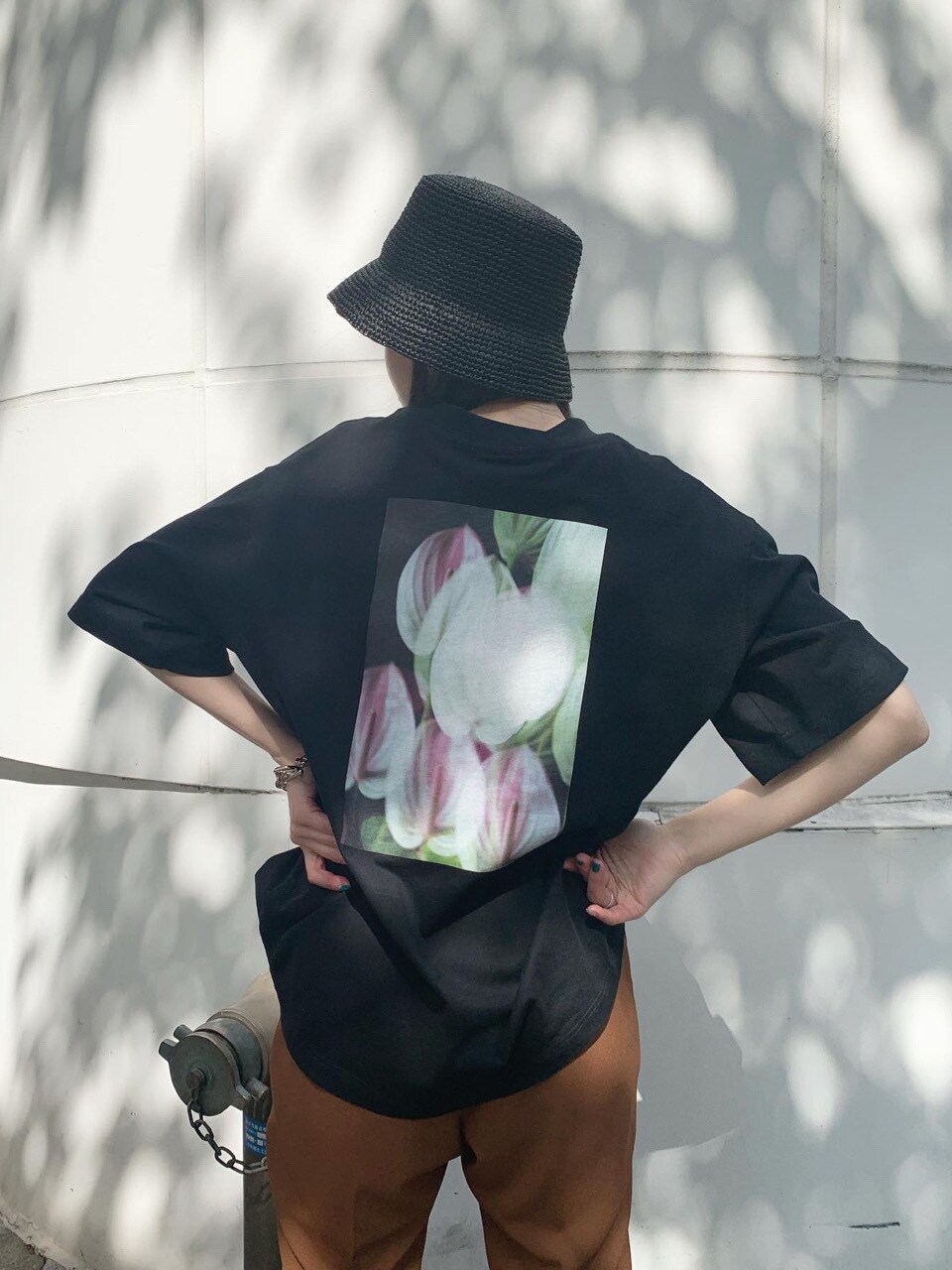 ブラック系のTシャツ/カットソー、ブラウン系のスラックス、ブラック系のハットを着用したレディースの春コーディネートの2枚目の写真