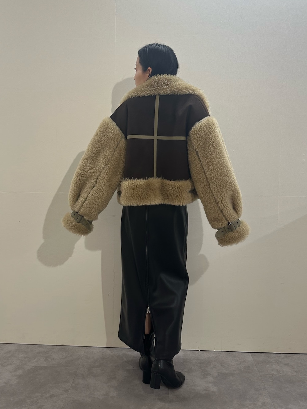 ブラック系のスカート、ブラウン系のムートンコート、レッド系のニット/セーターを着用したレディースの冬コーディネートの3枚目の写真