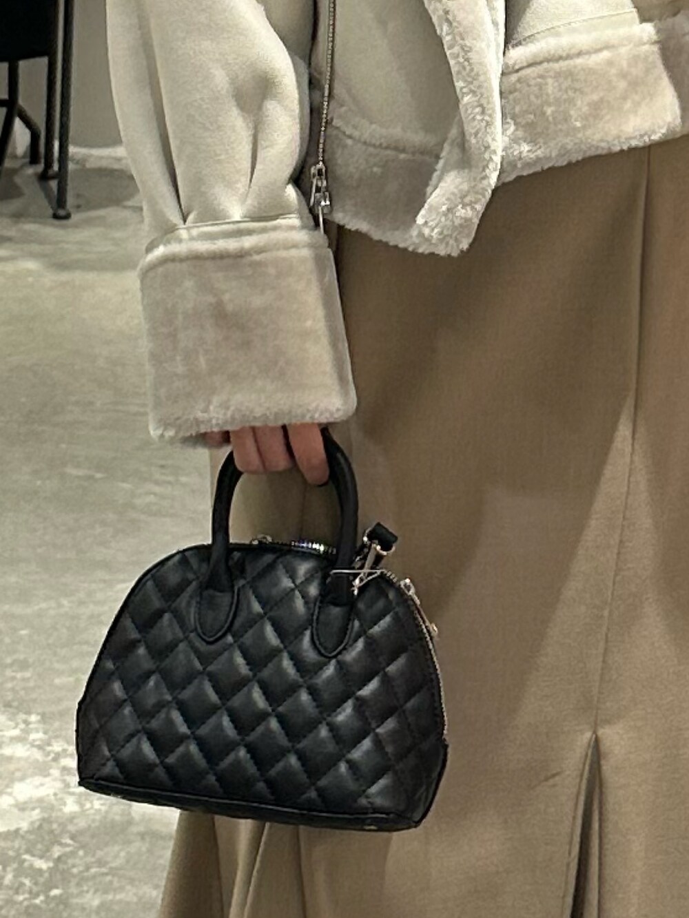 ベージュ系のスカート、グレー系のムートンコート、ブラック系のニット/セーターを着用したレディースの冬コーディネートの8枚目の写真