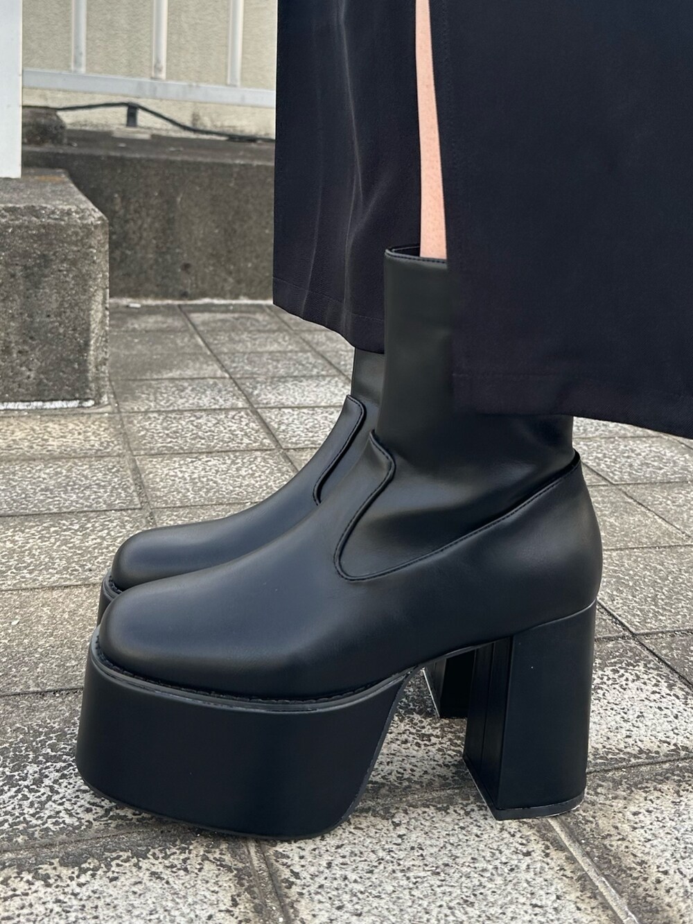 ブラック系のニット/セーター、ブラック系のスカート、ブラック系のブーツを着用したレディースの夏コーディネートの9枚目の写真