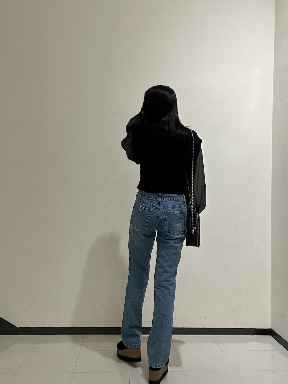 ブラック系のニット/セーター、ブルー系のデニムパンツを着用したレディースの春コーディネートの4枚目の写真