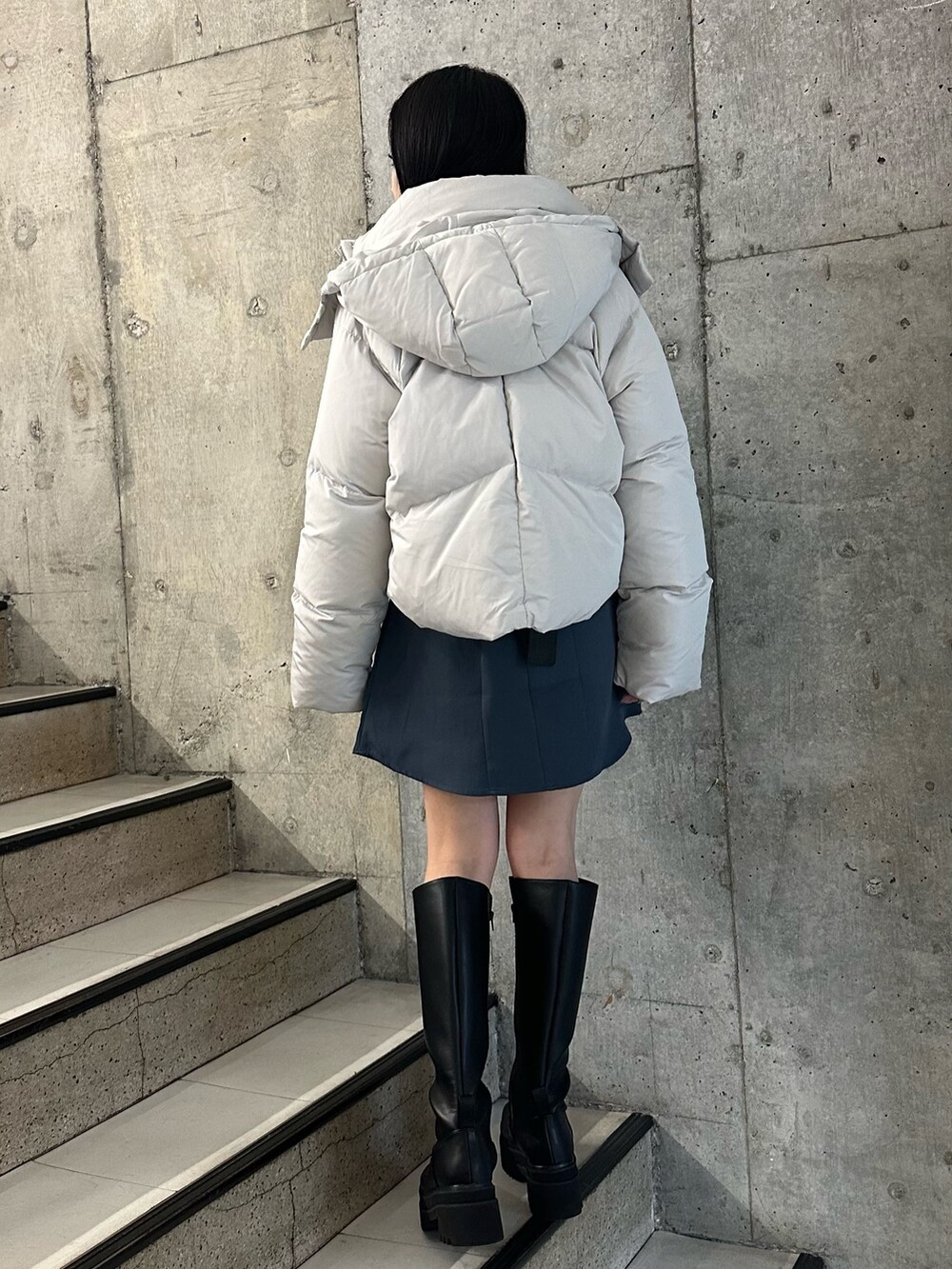 グレー系のワンピース、グレー系のダウンジャケット/コート、ブラック系のブーツを着用したレディースの冬コーディネートの2枚目の写真