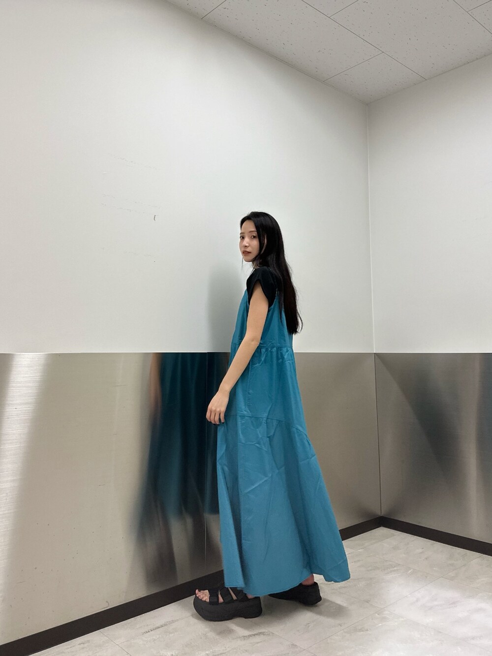 ブルー系のワンピース、ブラック系のTシャツ/カットソー、ブラック系のサンダルを着用したレディースの春コーディネートの3枚目の写真