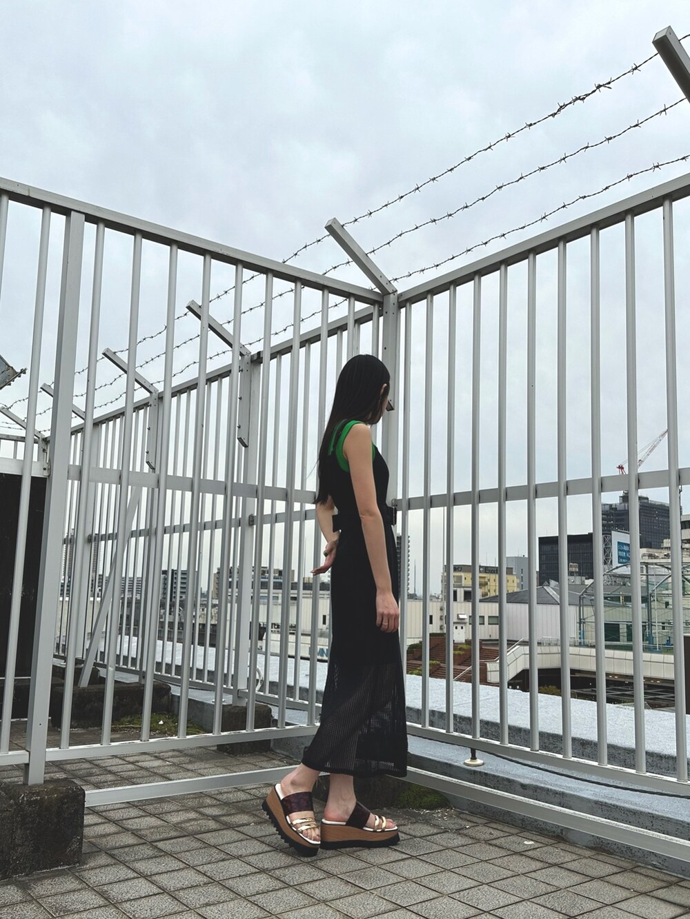 ブラック系のワンピース、グリーン系のタンクトップ、その他のサンダルを着用したレディースの春コーディネートの5枚目の写真