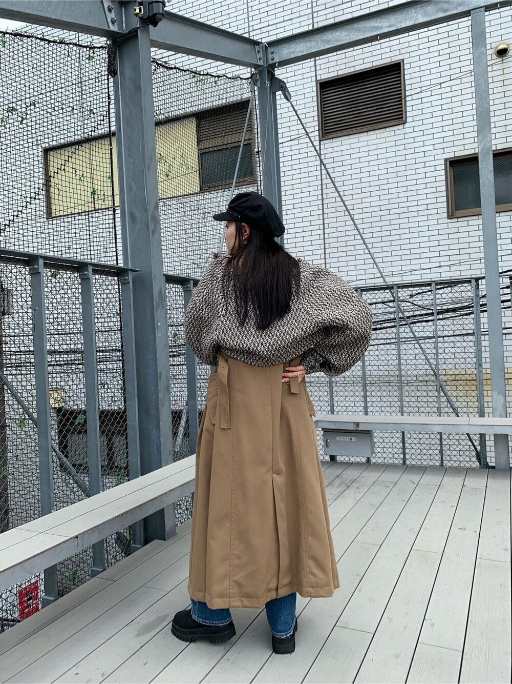 ブラック系のニット/セーター、ブルー系のデニムパンツ、ブラウン系のトレンチコートを着用したレディースの夏コーディネートの3枚目の写真