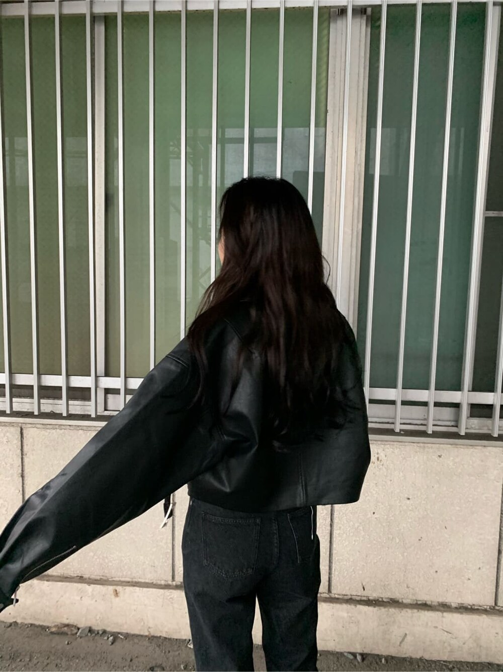 ブラック系のデニムパンツ、ブラウン系のブーツ、ブラック系のライダースジャケットを着用したレディースの秋コーディネートの4枚目の写真