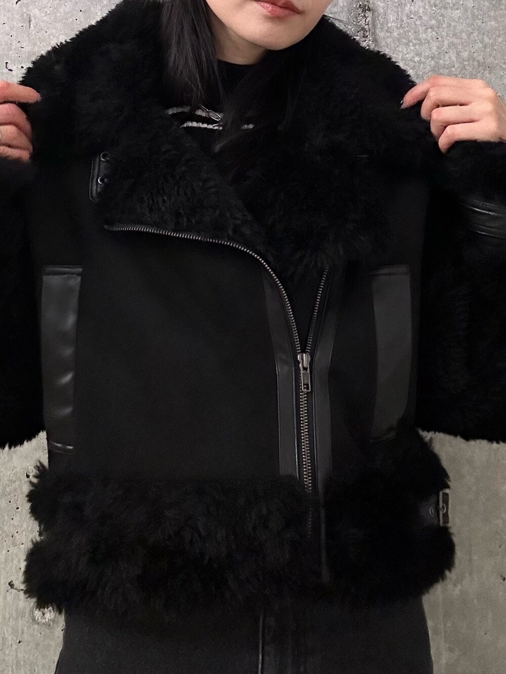 ブラック系のムートンコート、その他のニット/セーター、ブラック系のデニムパンツを着用したレディースの秋コーディネートの6枚目の写真